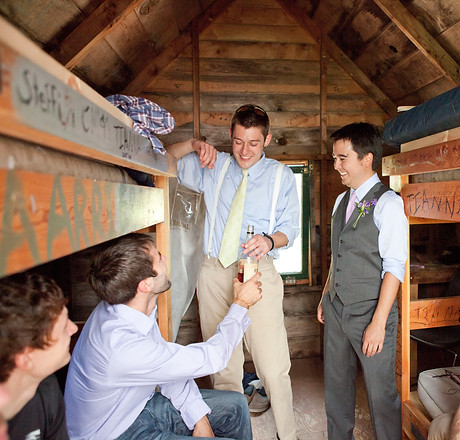 Groom and groomsmen relax in a rustic camper cabin.