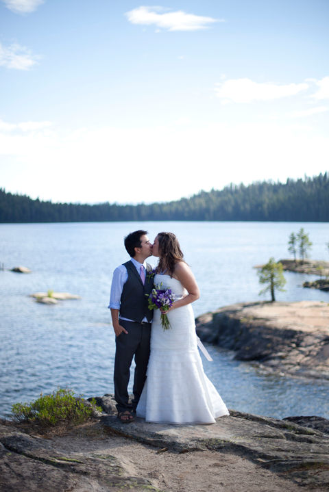 Wedding couple share a kiss with background of Payette Lake and small islands.
