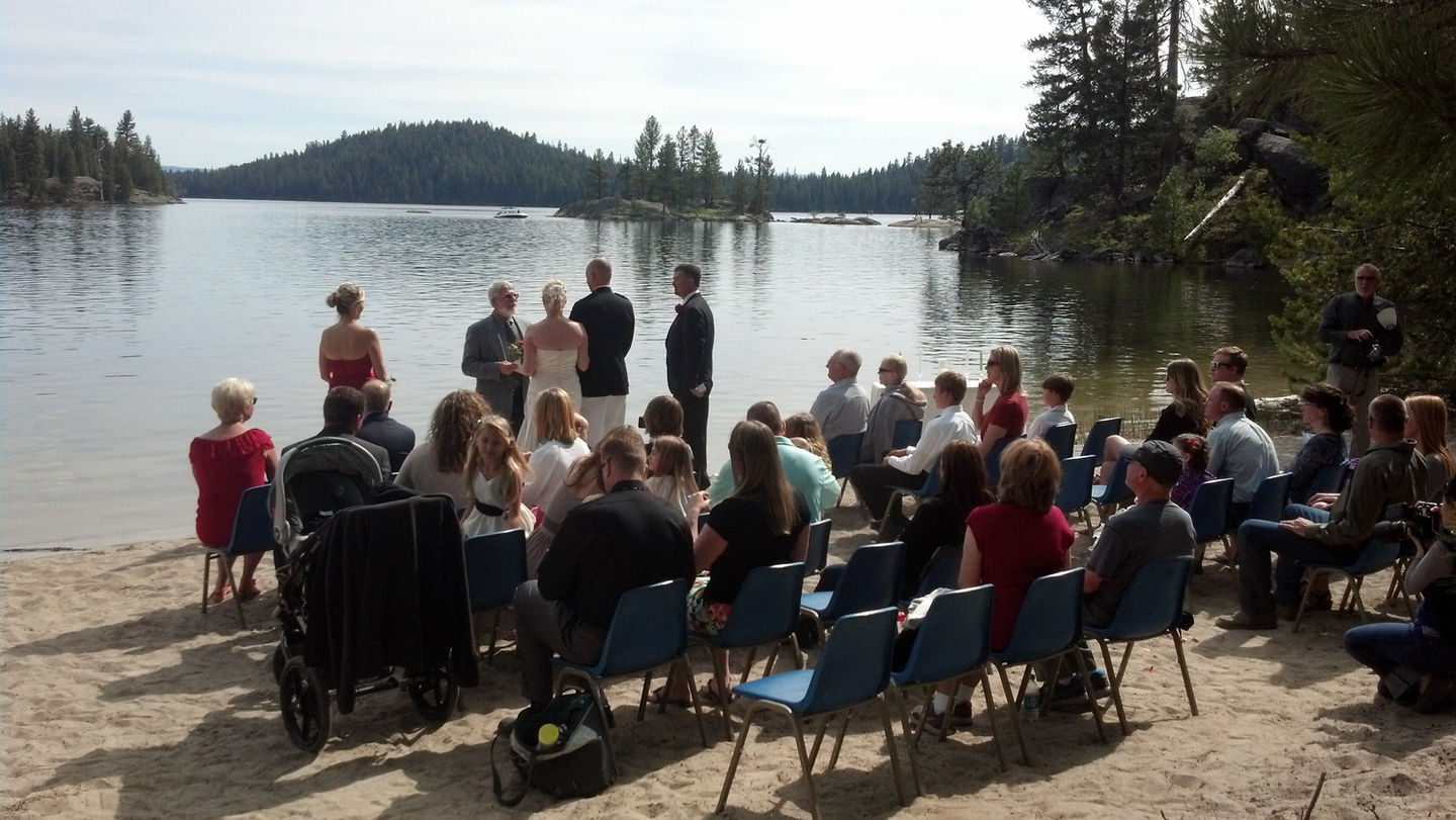 Small wedding ceremony on beach with view of lake.