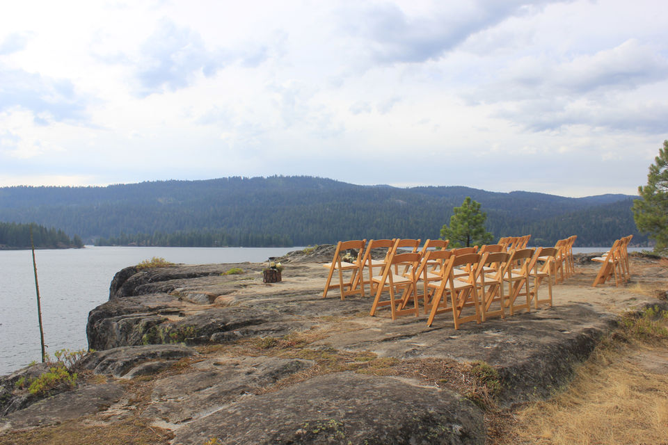 Wooden chairs on Paradise Point set for wedding ceremony with view of lake.